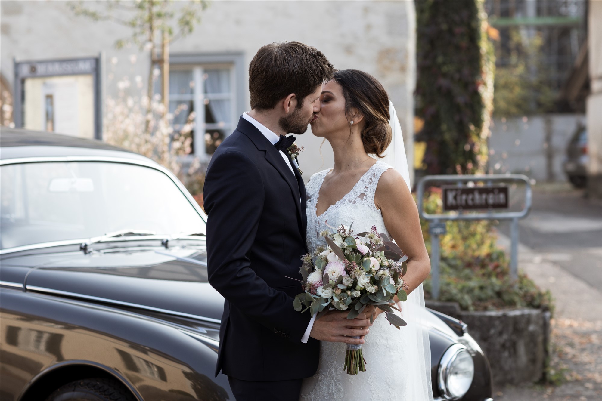 Das hübsche Brautpaar küsst sich vor der Kirche in Therwil