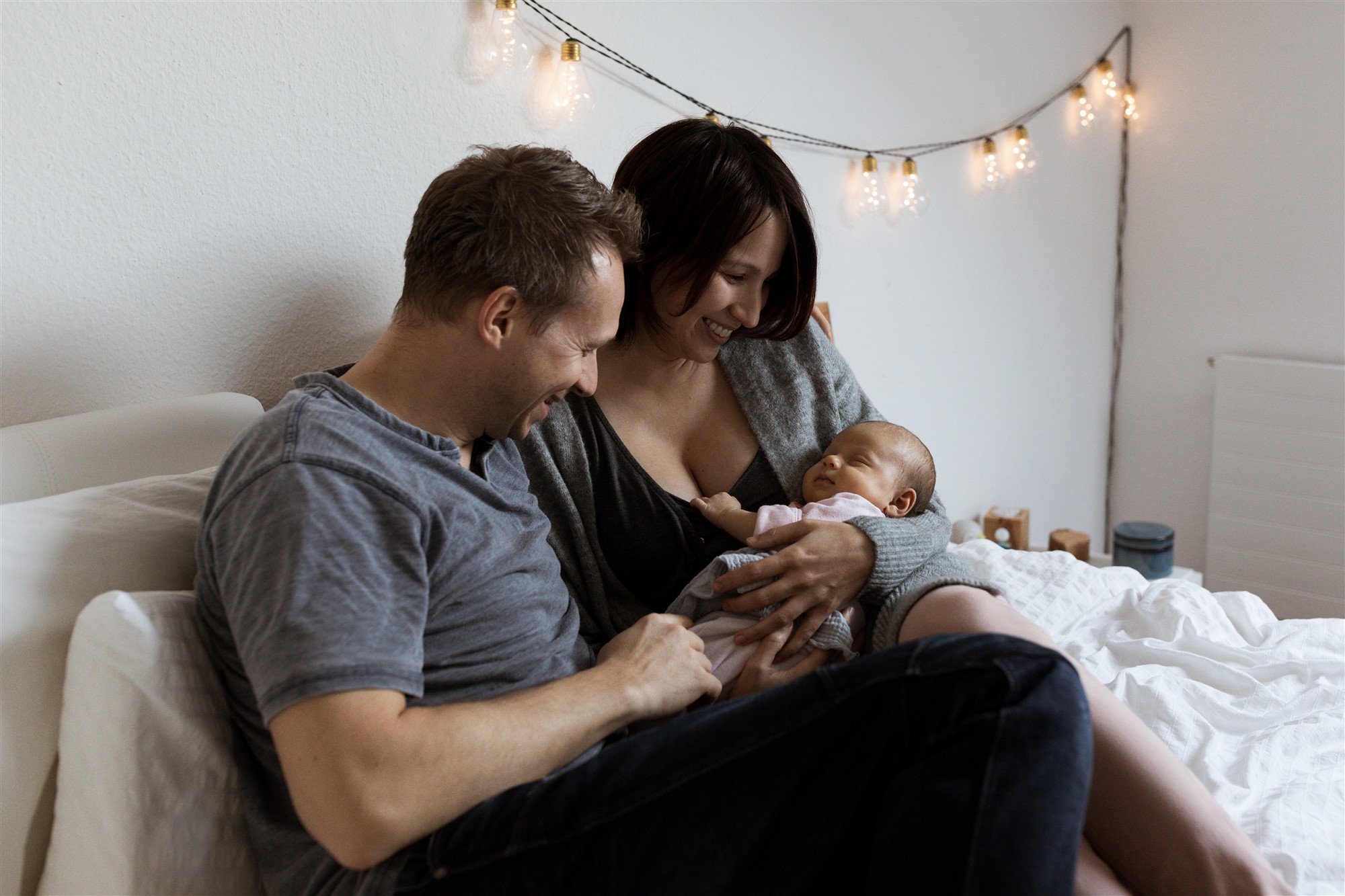 Newborn Homestory Fotoshooting - Die Eltern kuscheln mit ihrem Baby