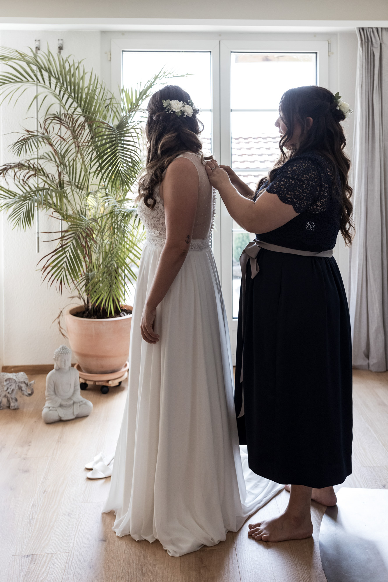 Die Schwester hilft beim Anziehen des Hochzeitskleides
